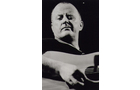 Download Foto: Schwarz-weiß-Foto von einer Person, die eine Akustikgitarre spielt. Die Person blickt konzentriert nach unten.