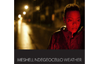 Download Foto: Eine Person im roten Licht, in einer nächtlichen Straßenszene. Text am unteren Rand: 'Meshell Ndegeocello Weather'.