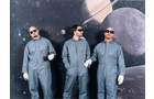 Download Foto: Drei Personen in grauen Anzügen und Sonnenbrillen vor einem Weltraumhintergrund mit Planeten und Monden.