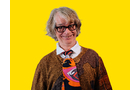 Download Foto: Eine Person mit Brille und grauen Haaren lächelt vor einem gelben Hintergrund. Sie trägt einen gemusterten Schal und Pullover.