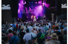 Download Foto: Menschenmenge bei einem Open-Air-Konzert, bunte Lichter auf der Bühne mit 'JAZZ' im Hintergrund, Abenddämmerung.