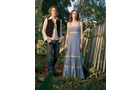 Download Foto: Zwei Personen stehen in einem Garten. Die Person links trägt Jeans und Weste, die rechts ein langes, blaues Kleid.