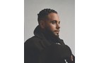 Download Foto: Ein Mann mit kurzem Haar und Bart blickt nach rechts. Er trägt eine dunkle Jacke und steht vor neutralem Hintergrund.