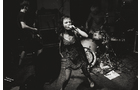 Download Foto: Eine Frau singt energisch auf der Bühne, begleitet von einer Band. Die Szene ist in Schwarzweiß gehalten, die Stimmung ist intensiv.