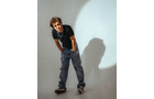 Download Foto: Eine Person mit Sonnenbrille lehnt sich nach vorne, trägt ein schwarzes T-Shirt und Jeans, vor einer grauen Wand mit Lichtkreis.