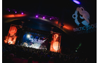Download Foto: Ein Konzert auf einer Bühne mit bunten Lichtern und einer großen Menschenmenge bei Nacht. Im Hintergrund ist ein Festival-Logo sichtbar.