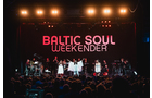 Download Foto: Eine Band auf der Bühne beim Baltic Soul Weekender, mit mehreren Sängern vor Publikum und beleuchtetem Hintergrund.