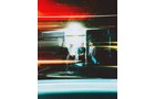 Download Foto: Verschwommene Nachtaufnahme von drei Personen vor heller Tür, mit dynamischen Lichtstreifen und Bewegungsunschärfe.