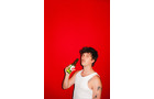 Download Foto: Person in weißem Tanktop hält eine Flasche vor einem leuchtend roten Hintergrund.