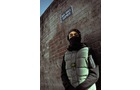Download Foto: Person in Winterkleidung steht an einer Ziegelwand, darüber ein Schild mit der Aufschrift Brick Lane.