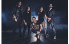 Download Foto: Eine fünfköpfige Rockband posiert vor einem nebligen, dunklen Hintergrund. Ein Mitglied hockt vorne, die anderen stehen dahinter.