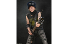Download Foto: Ein Musiker trägt Mütze und Weste, spielt E-Gitarre vor dunklem Hintergrund. Dynamische Pose, entschlossener Ausdruck.