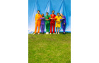 Download Foto: Fünf Personen in bunten Outfits stehen vor einem blauen Hintergrund auf einer Wiese.