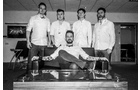 Download Foto: Fünf Männer in weißen Hemden, vier stehend, einer sitzt auf einem Sofa. Sie lächeln in die Kamera, das Bild ist in Schwarz-Weiß.