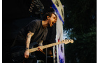 Download Foto: Ein Musiker mit E-Gitarre schreit leidenschaftlich auf einer Bühne während eines Open-Air-Konzerts.