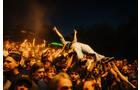 Download Foto: Ein Mensch in Jeans wird von einer Menge bei einem Konzert in der Nacht getragen, umgeben von leuchtenden Lichtern und jubelnden Zuschauern.