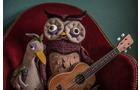 Download Foto: Plüsch-Eule und Vogel sitzen auf einem roten Sessel, die Eule hält eine Ukulele. Hintergrund ist grün.