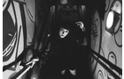 Download Foto: Eine Person mit schwarzer Kleidung steigt eine enge, grafittiüberzogene Treppe hinauf. Die Beleuchtung ist dramatisch.