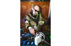 Download Foto: Ein DJ mit Sonnenbrille mixt Musik an einem DJ-Pult, umgeben von bunten Lichtreflexen und elektronischen Geräten.