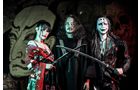 Download Foto: Drei Personen in kunstvollen Kostümen posieren mit Katana vor einer Wand mit Graffiti, im Stil von Cosplay oder einem Theaterstück.
