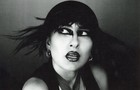 Download Foto: Schwarz-weiß-Foto einer Person mit dunklem Make-up, kurzen Haaren und auffälligem Gesichtsausdruck. Sie blickt zur Seite.