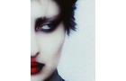 Download Foto: Verzerrte Nahaufnahme eines Gesichts mit dunklem Augen-Make-up und leuchtend roten Lippen, teils im Schatten.