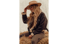 Download Foto: Person mit langem, blondem Haar, trägt einen Cowboyhut und sitzt auf einem Strohballen. Sie trägt eine Jacke und Hose.