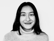 Frau mit langen dunklen Haaren und hellem Rollkragenpullover lächelt in die Kamera. Schwarz-weiß Foto vor neutralem Hintergrund.