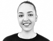 Porträt einer Person mit zurückgebundenem Haar, die lächelt. Schwarz-weiß Bild mit hellem Hintergrund.