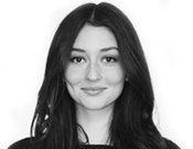 Eine lächelnde Frau mit langen, dunklen Haaren vor weißem Hintergrund, schwarz-weiß aufgenommen.