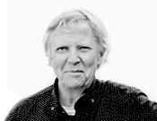 Porträt eines älteren Menschen mit hellem Haar und dunklem Oberteil vor einem weißen Hintergrund.