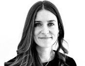 Eine Frau mit langen, glatten Haaren lächelt leicht in die Kamera. Das Foto ist in Schwarz-Weiß gehalten.