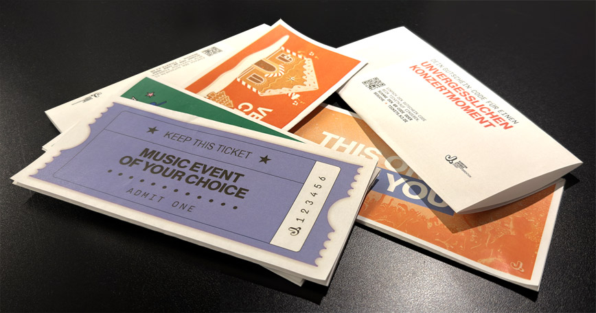 Mehrere bunte Konzert- und Gutschein­karten liegen auf einem Tisch.